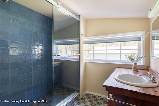 full bathroom featuring a stall shower, lofted ceiling, vanity, and baseboards