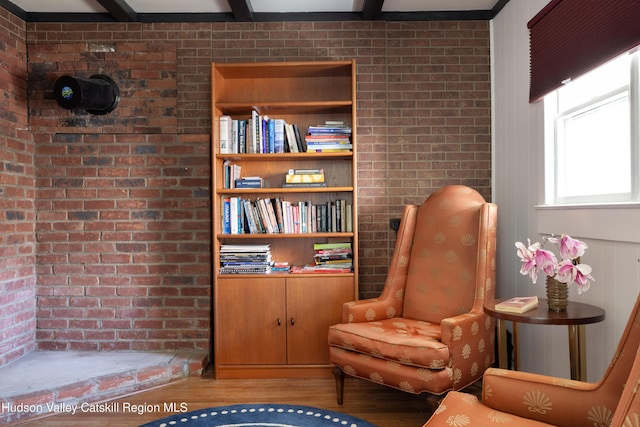 living area featuring wood finished floors and brick wall