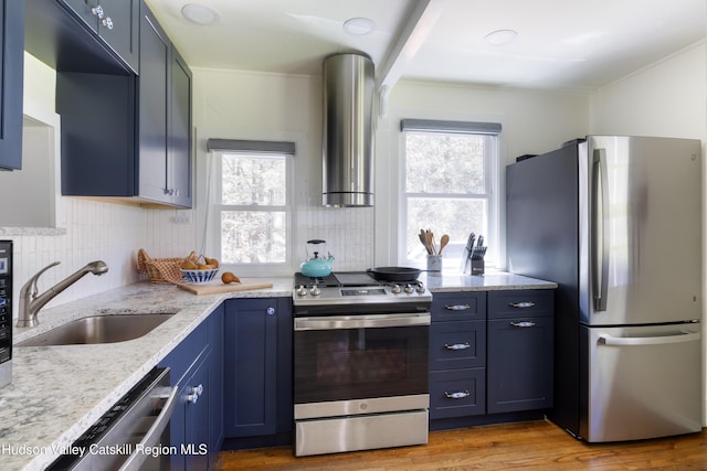 kitchen with stainless steel appliances, a sink, exhaust hood, blue cabinetry, and backsplash