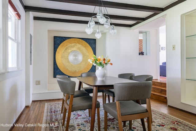 dining room featuring hardwood / wood-style floors, beamed ceiling, a chandelier, and baseboards