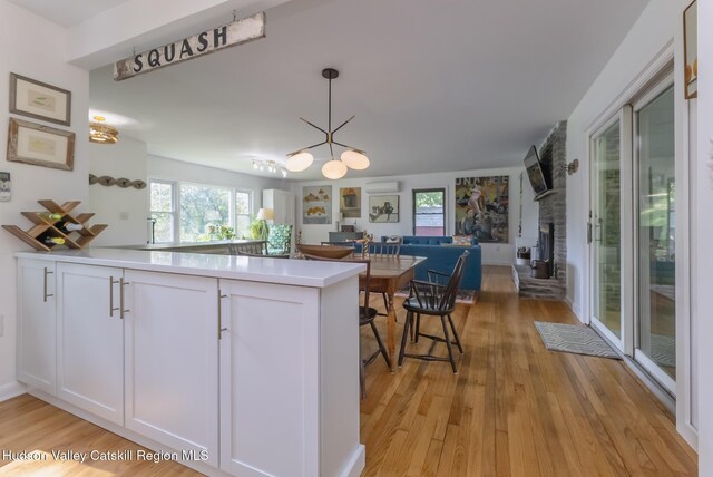 331 Joys Ln, Hurley, NY 12443 - kitchen with open floor plan, light wood-style floors, white cabinetry, and a large fireplace