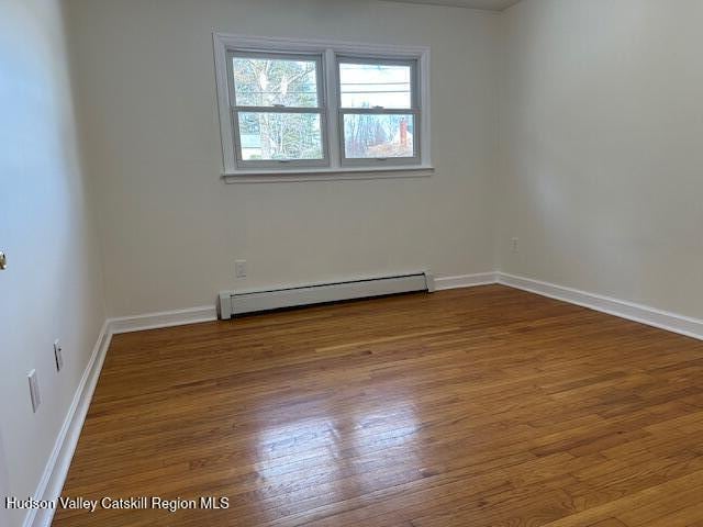 unfurnished room with baseboard heating and hardwood / wood-style flooring