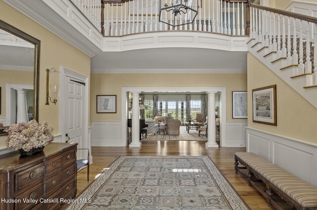 147 Moadock Rd, Millerton, NY 12546 - entrance foyer featuring ornate columns, a decorative wall, wood finished floors, ornamental molding, and a chandelier