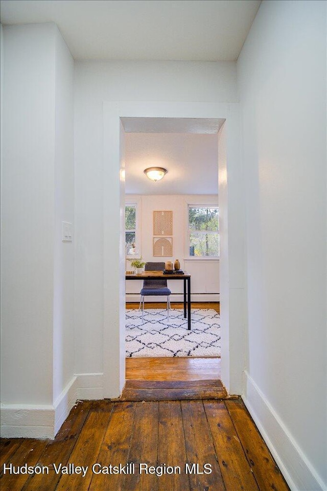 corridor with baseboards and hardwood / wood-style floors