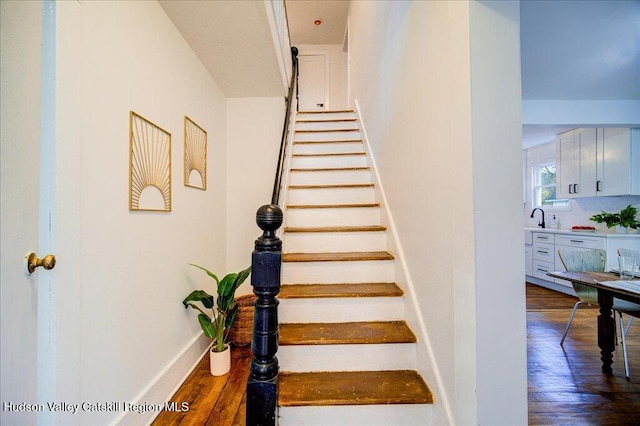 staircase featuring baseboards and wood finished floors