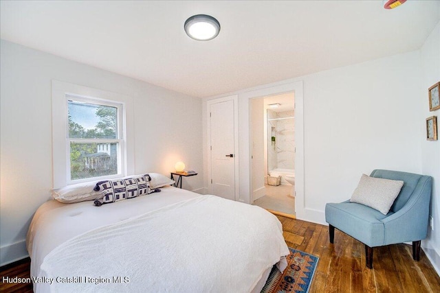 bedroom with baseboards, connected bathroom, and wood finished floors