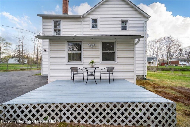 rear view of property with a wooden deck, a yard, a chimney, and fence