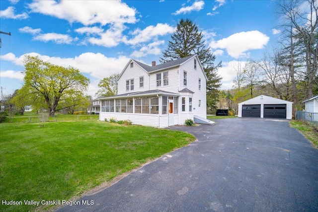 view of front of property featuring a garage, a sunroom, a front yard, an outbuilding, and a chimney