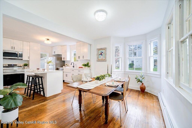 dining space with baseboards, baseboard heating, and light wood-type flooring
