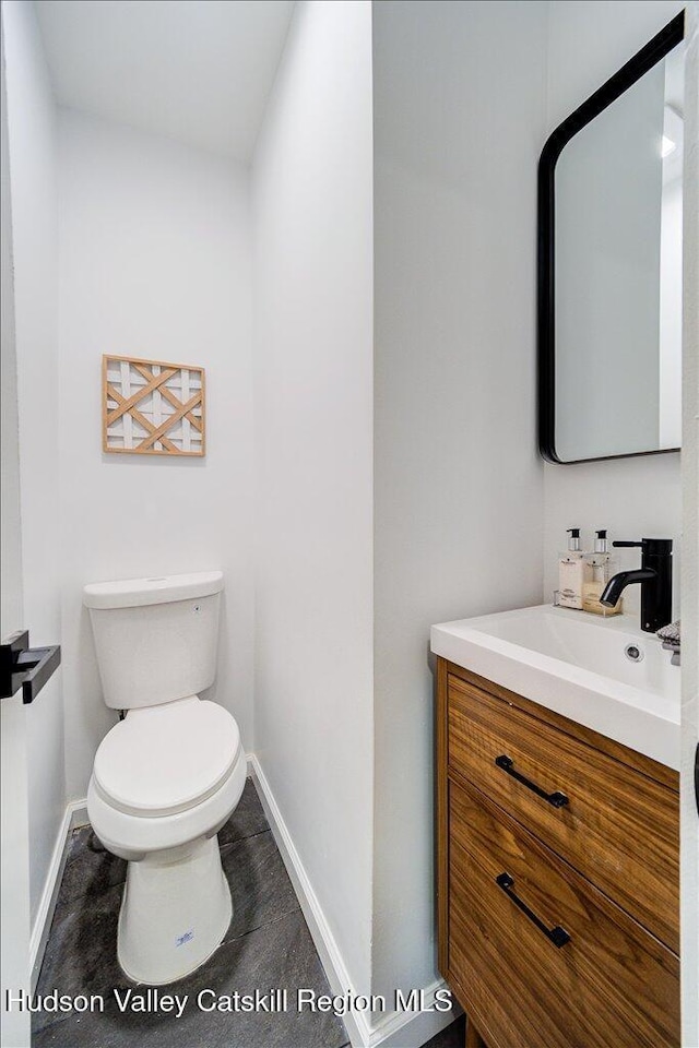 bathroom with baseboards, vanity, and toilet