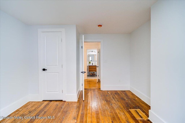 unfurnished room with baseboards and hardwood / wood-style floors