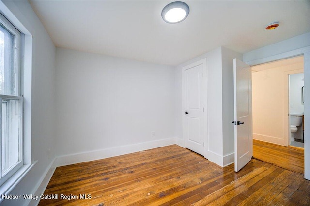 unfurnished bedroom with baseboards and hardwood / wood-style flooring