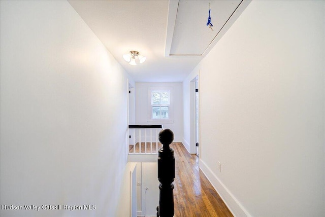 hallway featuring baseboards, light wood finished floors, and an upstairs landing