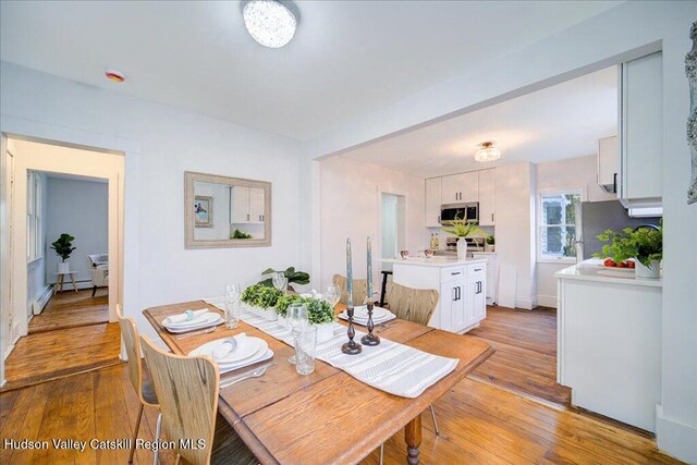 dining space with light wood-type flooring and baseboard heating