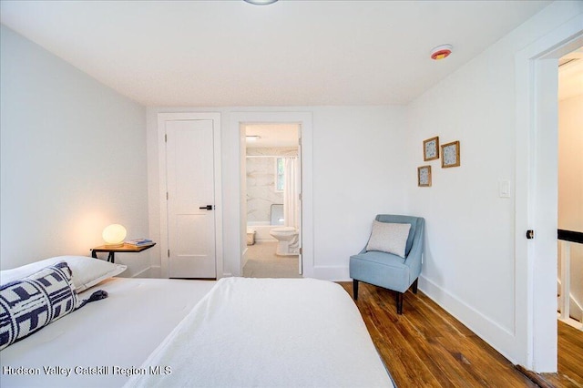 bedroom with connected bathroom, baseboards, and dark wood-type flooring