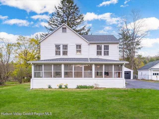 farmhouse-style home with a garage, an outbuilding, a sunroom, and a front lawn