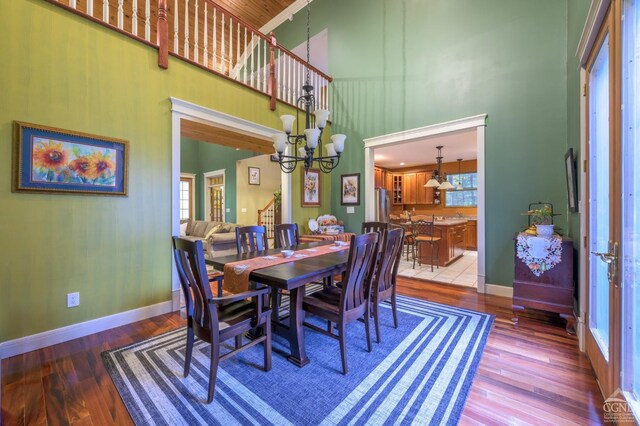 1013 Plank Rd, Averill Park, NY 12018 - dining space featuring a high ceiling, wood finished floors, a chandelier, stairs, and baseboards