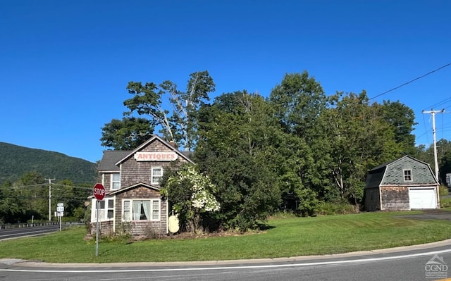 8176 Main St, Hunter, NY 12442 - view of front of property with a front lawn, a garage, an outbuilding, and a mountain view