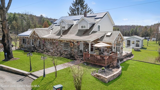 60-62 Stony Rd, Accord, NY 12404 - view of front of property featuring a chimney, a shingled roof, roof mounted solar panels, stone siding, and a front lawn