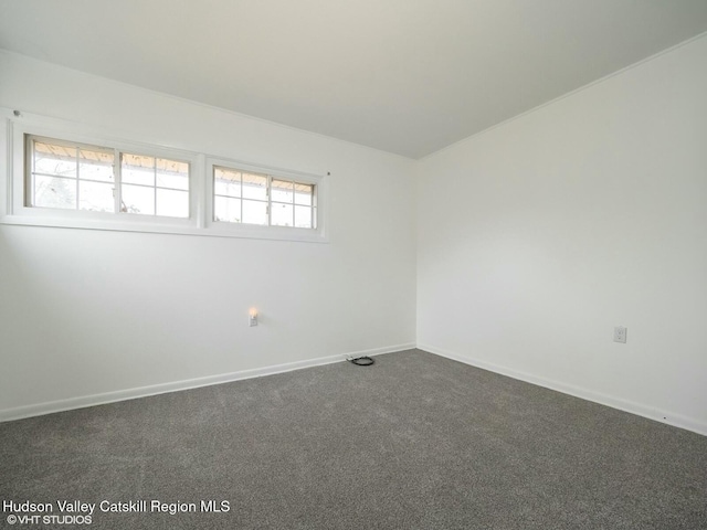 spare room featuring baseboards and dark colored carpet