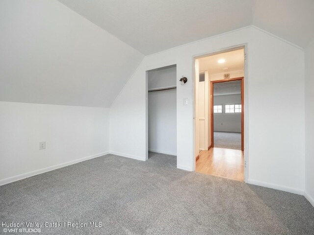 additional living space with carpet flooring, baseboards, and vaulted ceiling