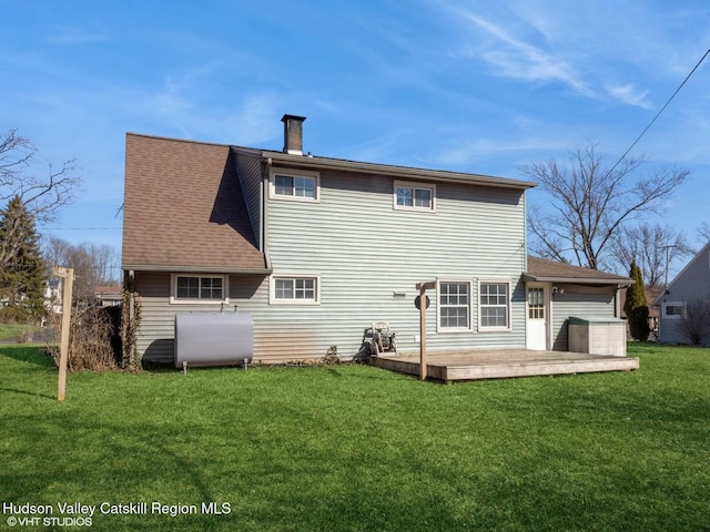 back of house featuring a yard, a chimney, a wooden deck, and heating fuel