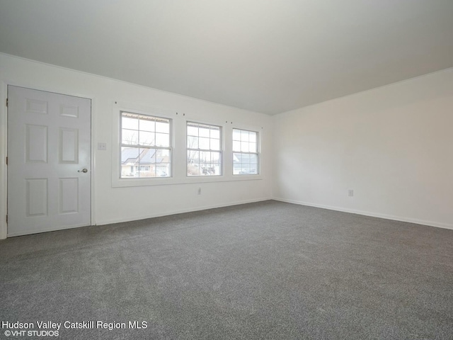 unfurnished room with dark colored carpet and baseboards