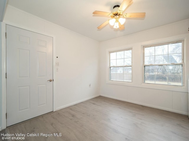 unfurnished room featuring ornamental molding, ceiling fan, wood finished floors, and baseboards