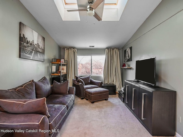 carpeted living room with ceiling fan and vaulted ceiling with skylight