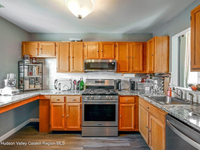 kitchen featuring sink, stainless steel appliances, dark hardwood / wood-style flooring, and light stone counters