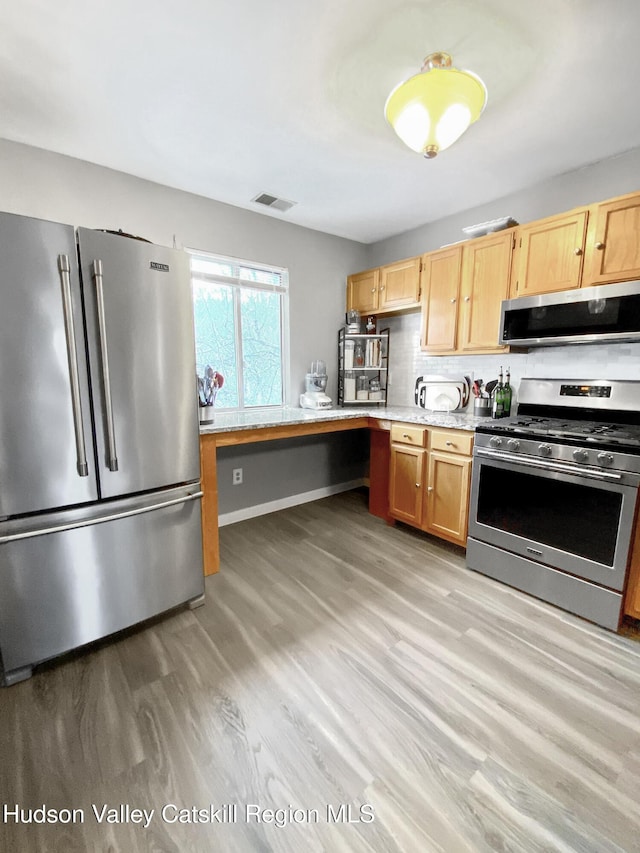 kitchen with appliances with stainless steel finishes, light hardwood / wood-style floors, decorative backsplash, and light brown cabinets