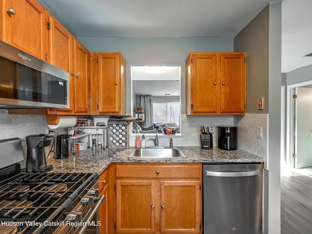 kitchen featuring stainless steel appliances, stone counters, backsplash, and sink