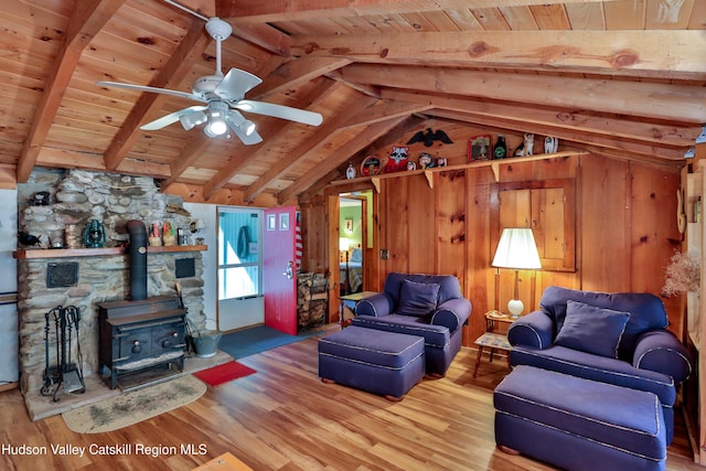 living room featuring hardwood / wood-style floors, lofted ceiling with beams, a wood stove, and wood walls