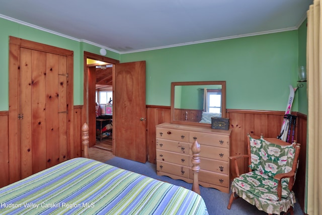 carpeted bedroom with wood walls and ornamental molding