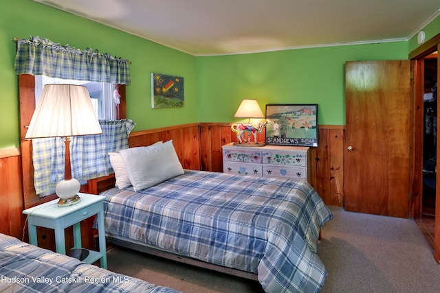 bedroom featuring wooden walls, crown molding, and carpet