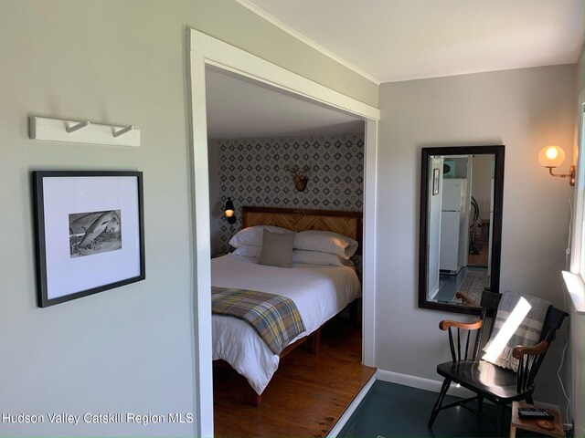 76 Smith Rd, Preston Hollow, NY 12469 - bedroom featuring wallpapered walls, an accent wall, freestanding refrigerator, and wood finished floors