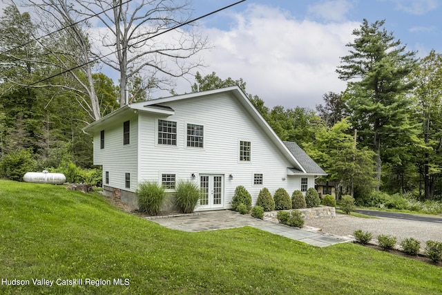 rear view of property with a patio, a lawn, and french doors