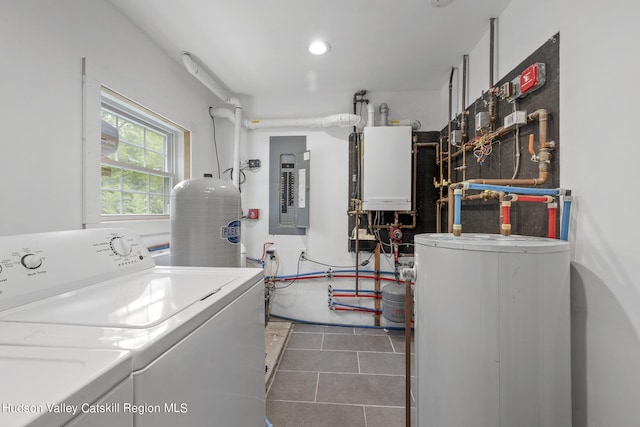 laundry area featuring water heater, dark tile patterned floors, electric panel, tankless water heater, and washing machine and clothes dryer