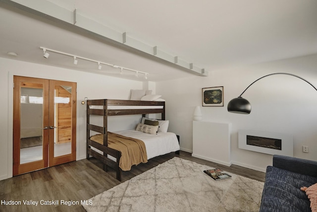 bedroom featuring hardwood / wood-style flooring, track lighting, and french doors