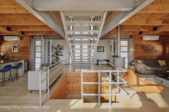 kitchen with wood ceiling, beam ceiling, wooden walls, an AC wall unit, and light wood-type flooring