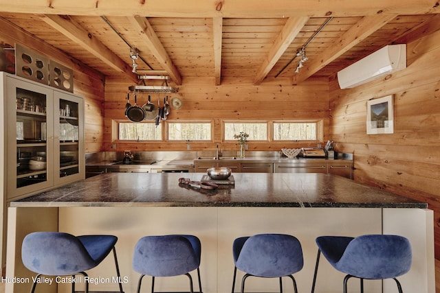 kitchen with an AC wall unit, wooden ceiling, a kitchen breakfast bar, and wood walls