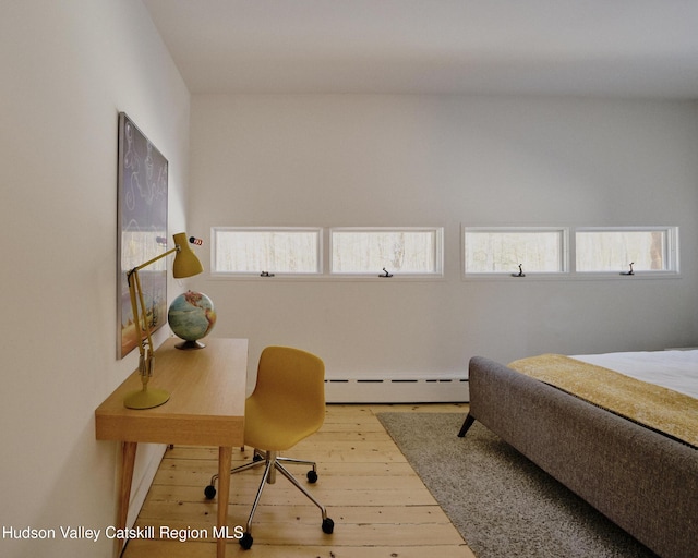 bedroom with a baseboard heating unit and hardwood / wood-style floors