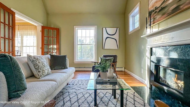 living room featuring baseboard heating, a fireplace, wood finished floors, a baseboard heating unit, and lofted ceiling