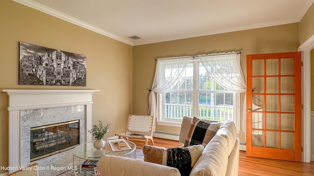 sitting room with visible vents, wood finished floors, a baseboard radiator, ornamental molding, and a premium fireplace
