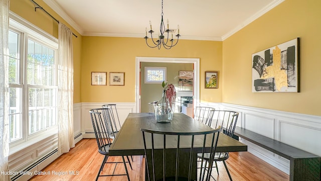 dining area with a decorative wall, a notable chandelier, ornamental molding, and light wood-type flooring