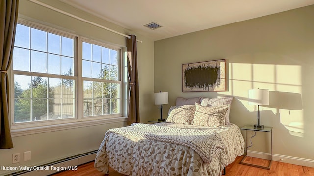 bedroom featuring visible vents, a baseboard radiator, baseboards, and wood finished floors