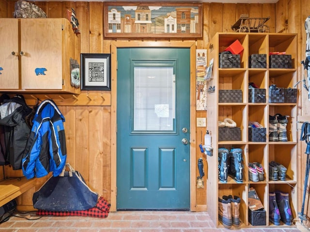mudroom with wooden walls and brick patterned flooring