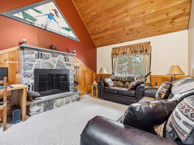 living area featuring carpet, lofted ceiling, wainscoting, wood ceiling, and a stone fireplace