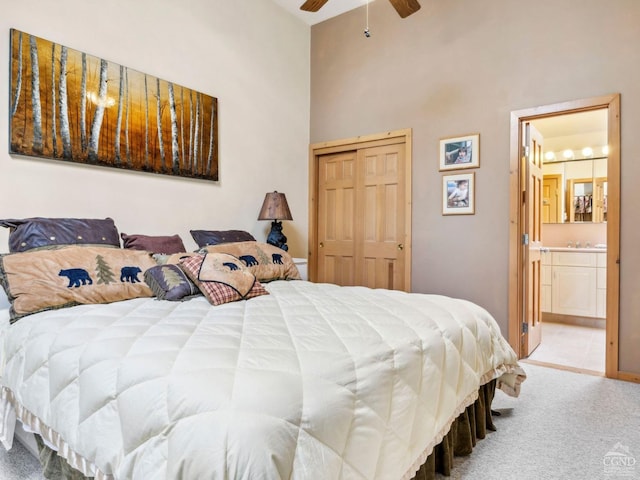 bedroom with carpet flooring, a high ceiling, a closet, ensuite bathroom, and a ceiling fan