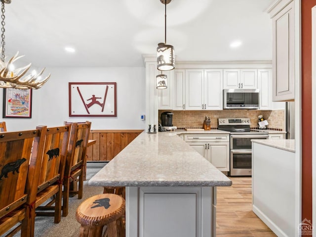 kitchen with stainless steel appliances, a peninsula, a breakfast bar, backsplash, and white cabinets